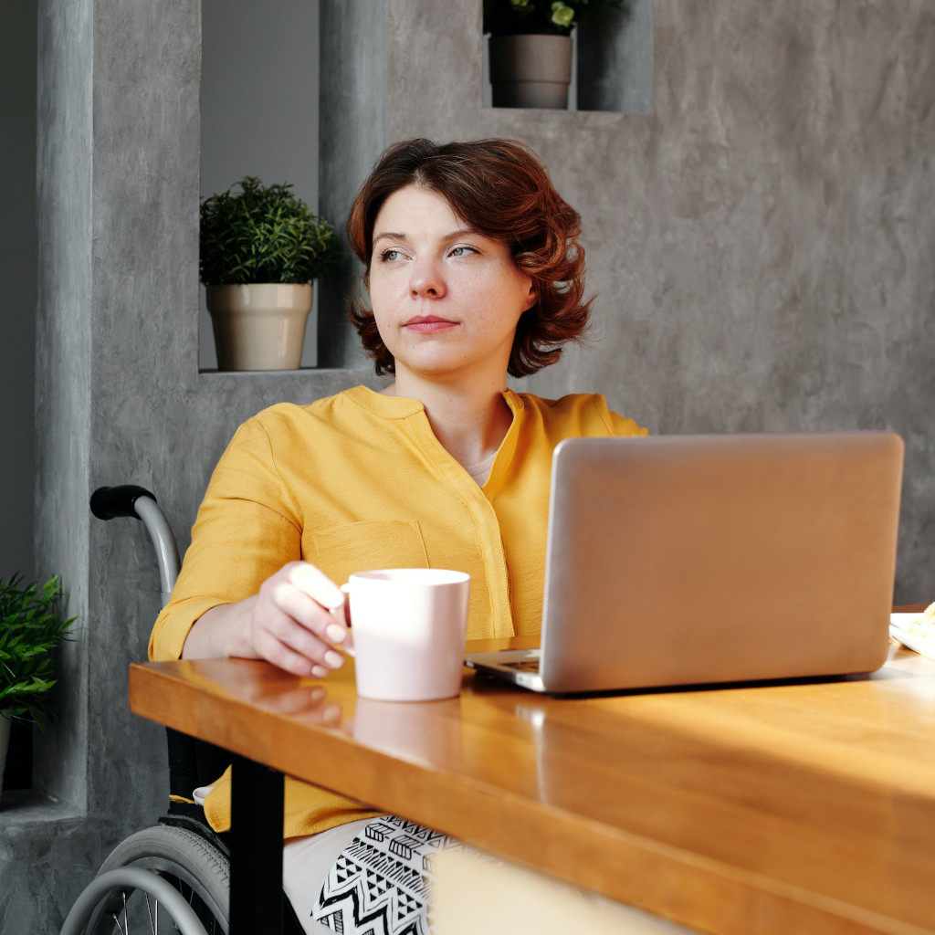 Journalling is a powerful tool for Developing Positive Habits - a young woman uses her laptop at a desk sitting in her wheelchair